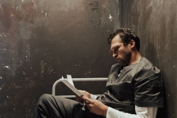 détenu lisant une lettre dans sa cellule de prison